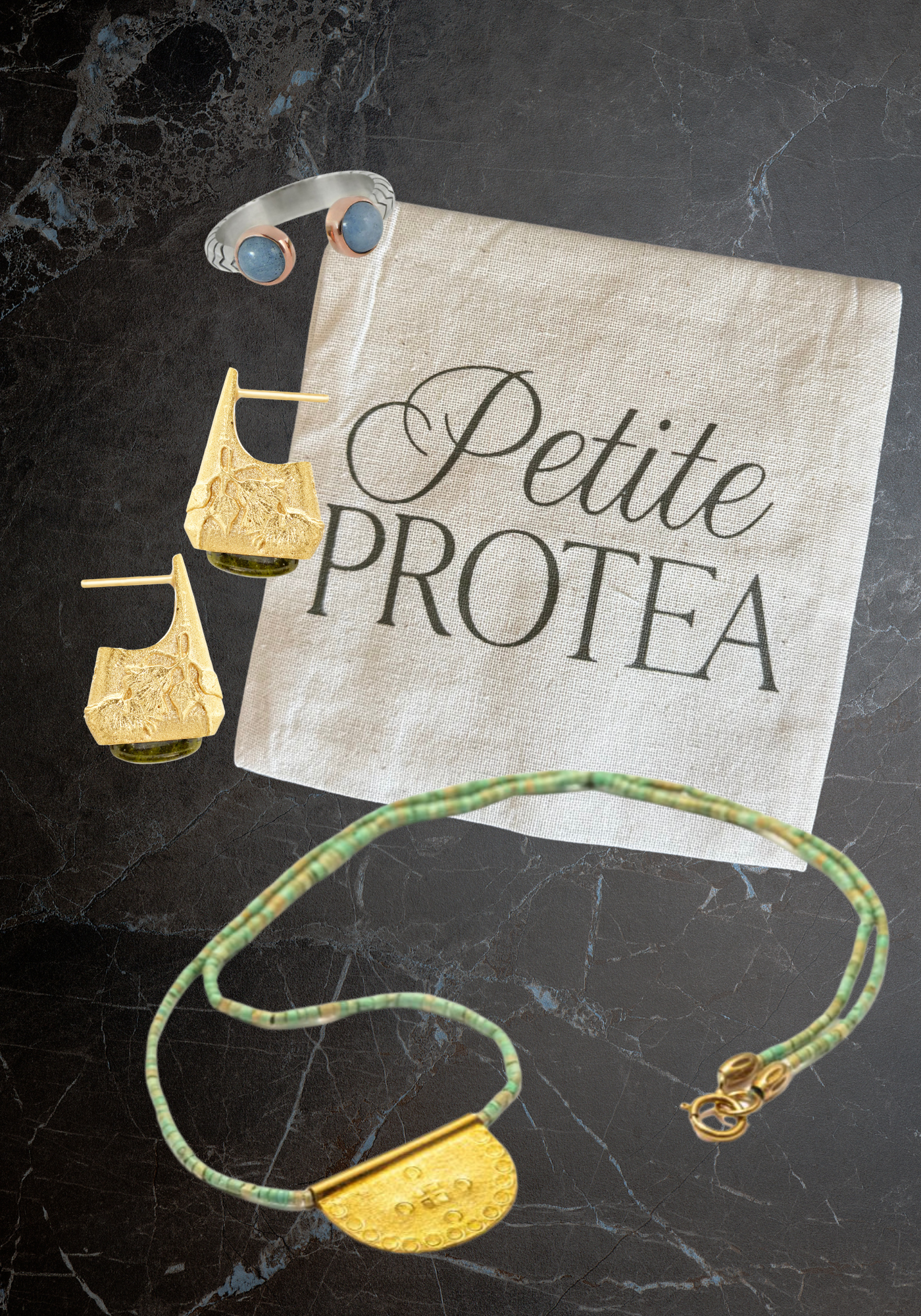 Silver Aquamarine ring, Handmade gold and jasper earrings, ethical turquoise and gold plated necklace in front of a Petite Protea jewelry bag