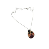 Ethically made, silver chain necklace with a ladybug pendant featuring purple and pink silk hand sewn on leather with ethically sourced bead stones and recycled materials, flay lay