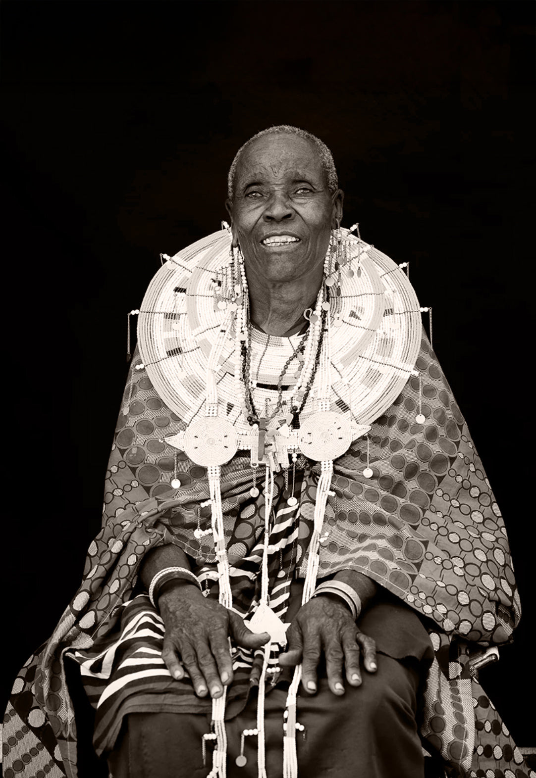 Black and white portrait of an elderly woman wearing traditional attire with a dark background